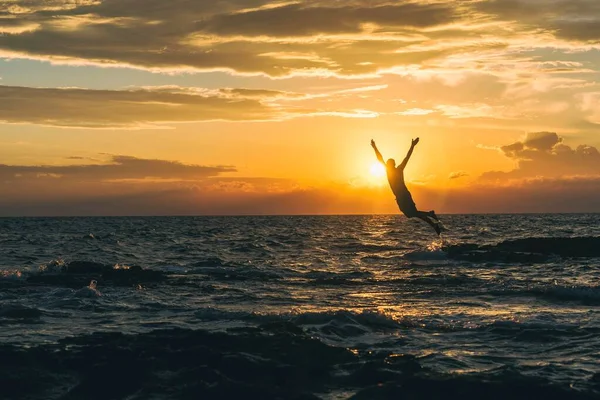 Men jump to adriatic sea durning sunset in Croatia
