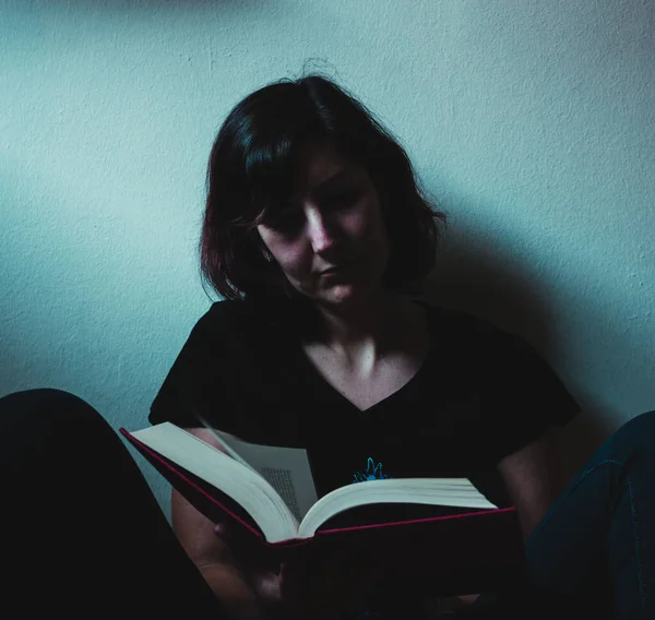 Karantina zamanında hafif ışıkla kitap okuyan bir kadın.