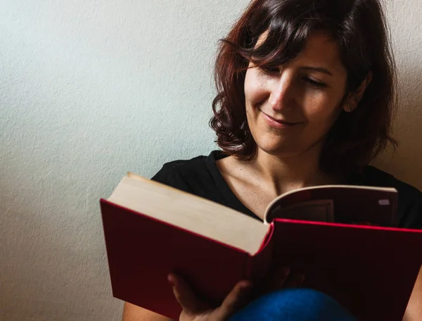 Karantina zamanında kitap okuyan bir kadın gülümseyerek....
