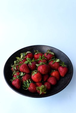 Kara Kasede Taze Çilek. Beyaz, Mavi ve Turuncu Arkaplan