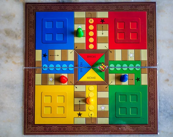Pieces and a die on a Ludo board game