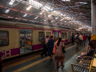 Mumbai, Hindistan - 18 Aralık 2019: Kimliği belirsiz yolcular sabahın erken saatlerinde Mumbai 'deki işçi sınıfının en yoğun tren istasyonlarından biri olan CST istasyonunda güneş ışınlarıyla platformda yürüyorlar.