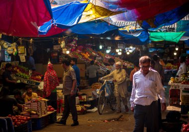 Mumbai, Hindistan - 18 Aralık 2019: Müslüman yaşlı adam geleneksel İslami giysiler giyiyor ve kafatası şapkası takıyor Güney Mumbai 'de bir meyve pazarında bisikletle yürüyor