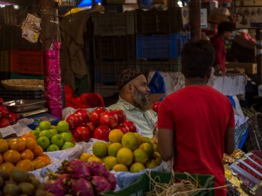 Mumbai, Hindistan - 18 Aralık 2019: Crowford pazarında Müslüman meyve satıcısı. Meyve satıcıları Hint şehirleri ve şehirleri boyunca yol kenarındaki dükkanlarda çeşitli meyveler satıyorlar..
