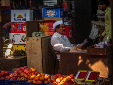 Mumbai, Hindistan - 18 Aralık 2019: Crowford pazarında geleneksel şapkalı Hint meyve satıcısı. Meyve satıcıları Hint şehirleri ve şehirleri boyunca yol kenarındaki dükkanlarda çeşitli meyveler satıyorlar..