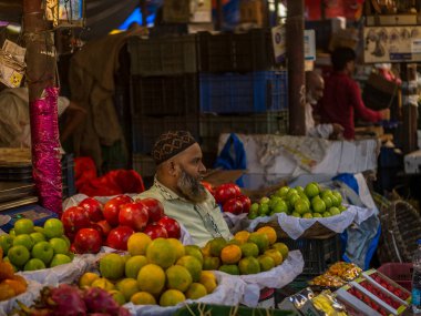 Mumbai, Hindistan - 18 Aralık 2019: Crowford pazarında Müslüman meyve satıcısı. Meyve satıcıları Hint şehirleri ve şehirleri boyunca yol kenarındaki dükkanlarda çeşitli meyveler satıyorlar..