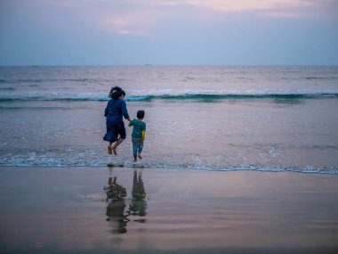 Malvan, Hindistan - 20 Aralık 2019: Neşeli Hintli Anne ve Oğlu Tarkarli Sahili 'nde atlayıp oynuyorlar