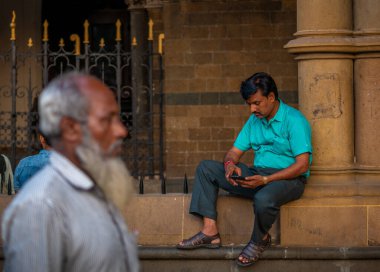 Mumbai, Hindistan - 26 Ocak 2020: CST istasyonu yakınlarındaki işlek bir caddede cep telefonu izleyen tanımlanamayan Hintli adam