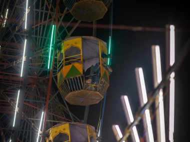 Mumbai, Hindistan - 01 Aralık 2019: Kimliği belirsiz bir çocuk Hindistan 'da gece aydınlanan lunaparktaki dev tekerlekten el sallıyor