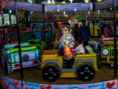 Mumbai, Hindistan - 01 Aralık 2019: Hintli çocuklar lunaparktaki açık bir arabada atlıkarınca sürüşünün keyfini çıkarıyorlar