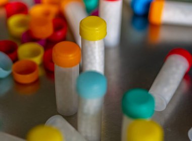 Beyaz homeopatik haplarla dolu renkli plastik şişeler.