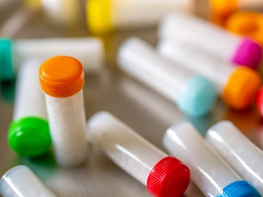 Beyaz homeopatik haplarla dolu renkli plastik şişeler.