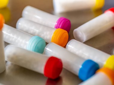 Beyaz homeopatik haplarla dolu renkli plastik şişeler.