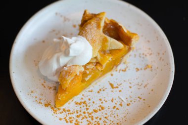 beyaz plaka üzerinde krem kırbaçlama ile şeftali pasta.