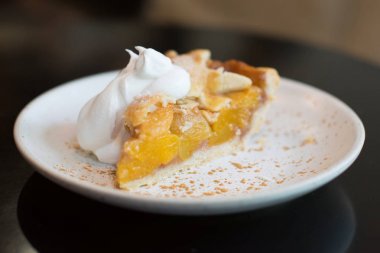 beyaz plaka üzerinde krem kırbaçlama ile şeftali pasta.