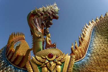 Mavi gökyüzü ile yedi başlı yılan üzerinde oturan Buda heykeli.