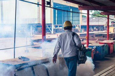 İnsanlar endüstriyel fabrikadaki sivrisinek ve böceklerden kurtulmak için sis makinesi kullanıyorlar..
