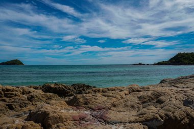 Taş ön planda ve deniz mavi gökyüzü ile arka planda.