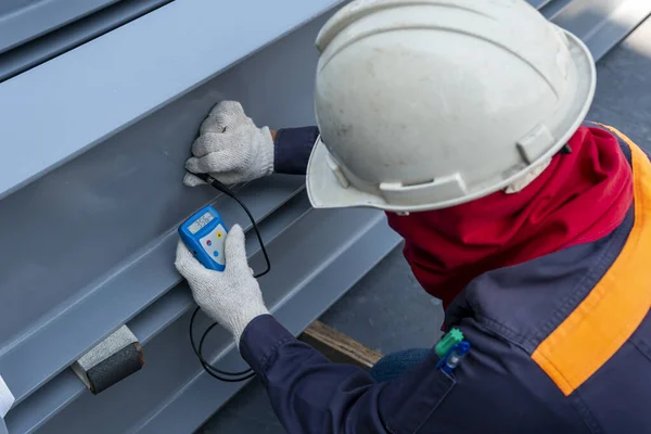 Technicians are measuring the Dry Film Thickness (DFT) with Coating Thickness Gauge for painting of steel structure work in industrial factory.