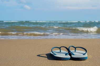 Sahilde sandaletler, arka planda deniz ve gökyüzü.