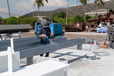 Ressam çelik yapının üzerine boya sürmeye çalışıyor. Sprey tabancayla, endüstriyel fabrikada..