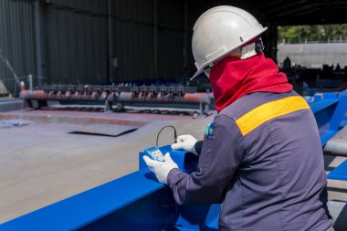 Teknisyenler, endüstriyel fabrikadaki çelik yapının boyanması için Kalın Kaplama Ölçeği (DFT) ile Kuru Film Kalınlığını ölçüyorlar..