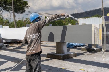Ressam çelik yapıdaki boyayı endüstriyel fabrikada sprey tabancayla ateşe dayanıklı hale getirmeye çalışıyor..