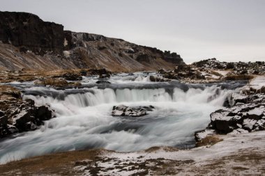 Kışın, bulutlu bir günde nehir akıntısı. Viking topraklarını zar zor keşfedebildik. İzlanda, Avrupa.