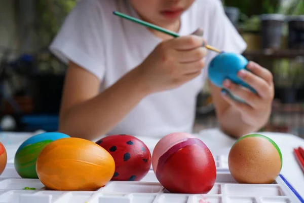 Easter concept, kid painting fancy colorful eggs for Easter event