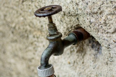 Duvarda eski metal su musluğu.