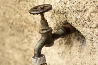 Duvarda eski metal su musluğu.