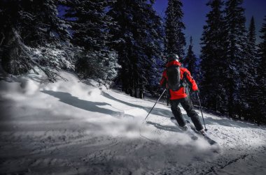 Kayakçı kışın, geceleri dağdan ormana iniyor.
