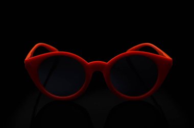 Kırmızı güneş gözlükleri siyah arkaplanda yatıyor.