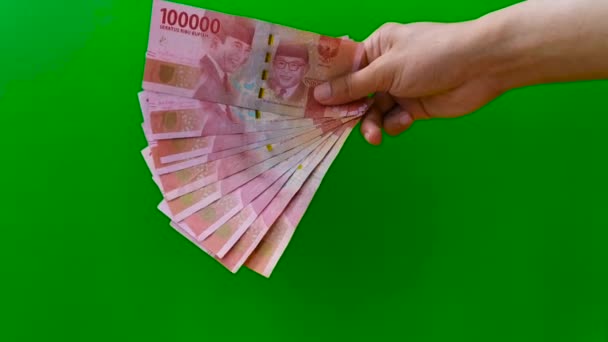 แสดงเงินรูปีอินโดนีเซีย 100000 (หนึ่งแสนรูปี) 10 ธนบัตรในปริมาณ 10,00000 รูเบียบนพื้นหลังสีเขียว — วีดีโอสต็อก
