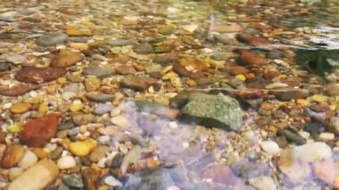 Sığ nehirde nehir taşları ve berrak su. Taze, şeffaf bir dağ nehri suyundaki taşlara yakın.