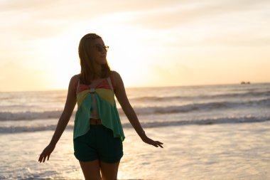 Sahilde, sabah gün ışığında yürüyen kadın