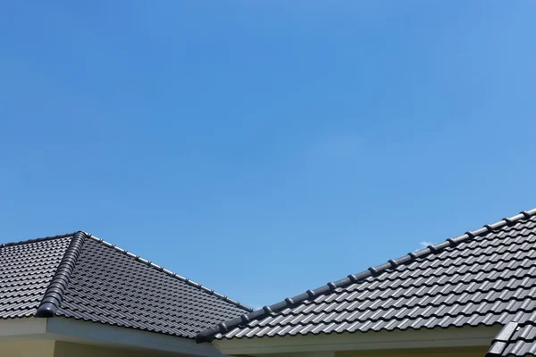 澄んだ青い空と雲の家に黒瓦の屋根 — ストック写真