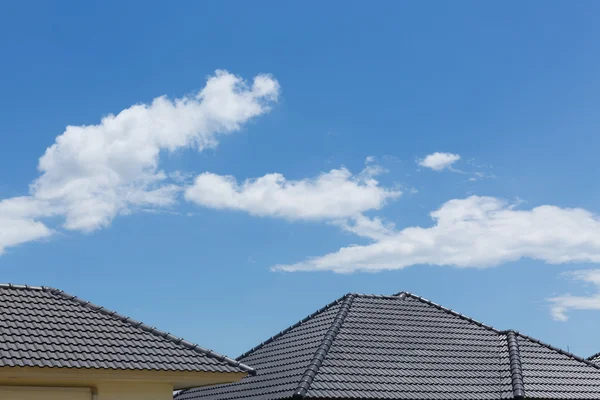 澄んだ青い空と雲の家に黒瓦の屋根 — ストック写真