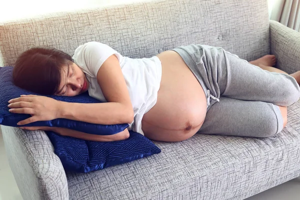 Mujer embarazada durmiendo en muebles de sofá en sala de estar — Foto de Stock