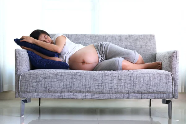 Žena těhotná, spaní na sedací nábytek v obývacím pokoji — Stock fotografie