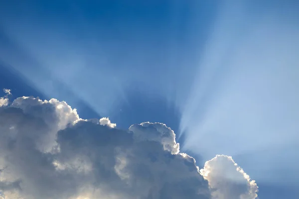 sun rays through cloud above clear blue sky