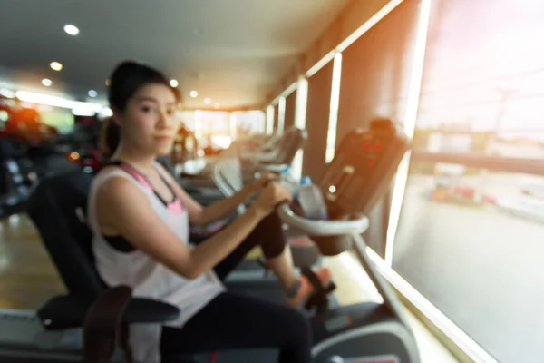 Wazig vrouw fietsen branden vet op fiets cardio machine — Stockfoto