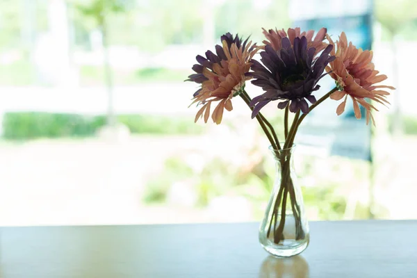 Beautiful artificial flower in small glass vase — Stock Photo, Image