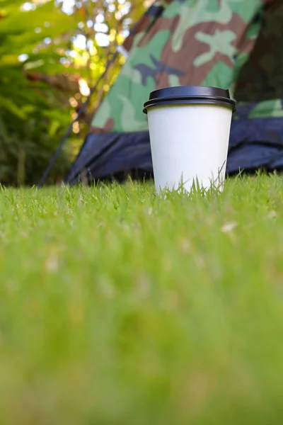 Гарячий кавовий напій, біла одноразова чашка на зеленій траві — стокове фото
