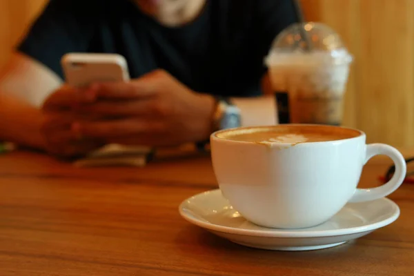 Bebida de café quente no café e as pessoas que trabalham no aplicativo inteligente móvel — Fotografia de Stock