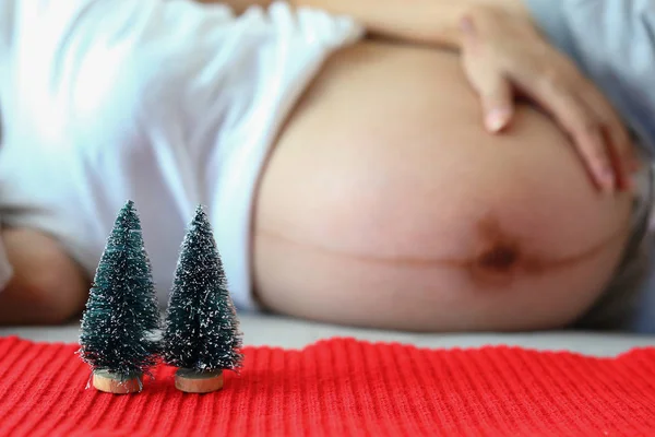 Kleiner Weihnachtsbaum auf rotem Garn mit schwangerer Frau — Stockfoto