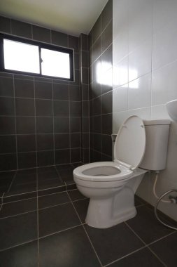 Beyaz tuvaletli küçük banyo tasarımı ve siyah fayans duvarı ve zemin.