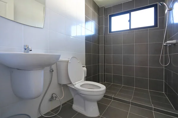 Desain modern kamar mandi kecil dengan lemari air toilet putih dan menggunakan dinding ubin hitam dan lantai — Stok Foto