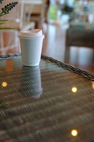 Tasse à emporter pour boire un café chaud mis sur une table en verre dans un café — Photo