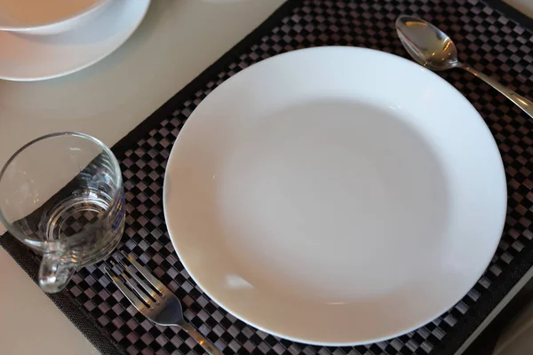 Beyaz tabak takımları yemek masasının üzerinde modern ev içi yemek odasının içinde. — Stok fotoğraf